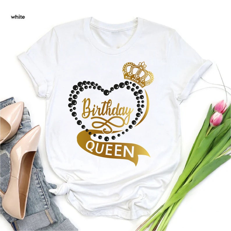 May include: White t-shirt with a gold crown and heart design. The heart is outlined with black beads and the text "Birthday Queen" is written in gold.