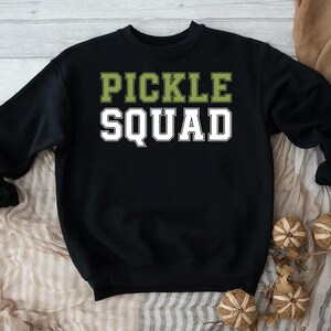 May include: Black sweatshirt with the text "Pickle Squad" in green and white letters.