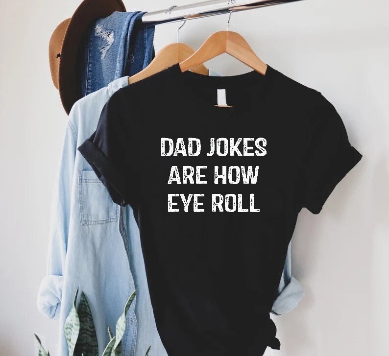 May include: Black t-shirt with white text that reads "Dad Jokes Are How Eye Roll".