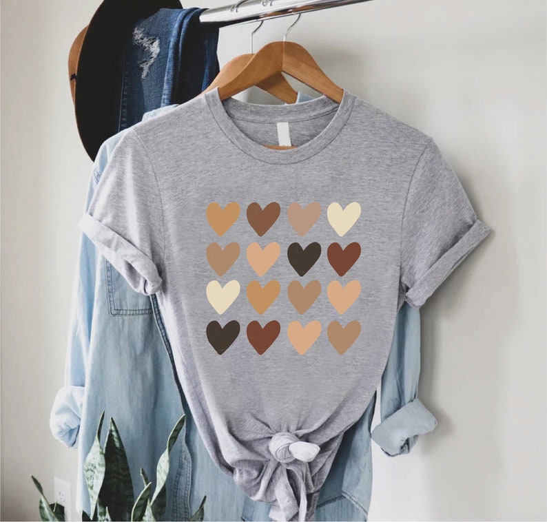 May include: A gray t-shirt with a design of 16 brown, beige, and cream hearts arranged in a grid.