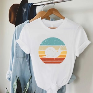 a t - shirt hanging on a clothes rack next to a plant