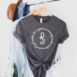 May include: A dark grey t-shirt with a white circle design featuring the Leo zodiac symbol and the words "Leo", "generous", "caring", "optimistic", "loyal", "fun", "open", "nature", "creative", and "warm".