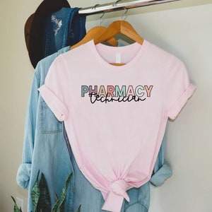 May include: Pink t-shirt with the text "Pharmacy Technician" in colorful letters.