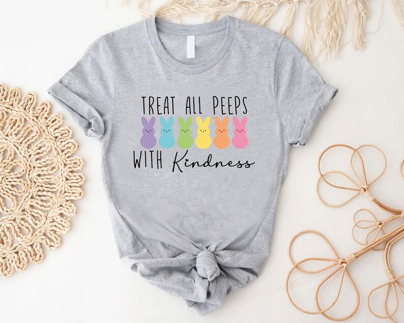 May include: A grey t-shirt with a graphic of colourful Peeps and the text "Treat all peeps with kindness".