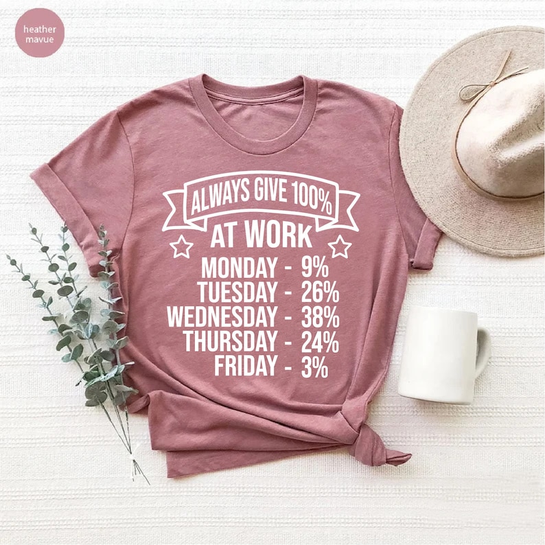May include: A heather mauve t-shirt with the text "ALWAYS GIVE 100% AT WORK" and a list of days of the week with percentages next to them. The percentages are: Monday - 9%, Tuesday - 26%, Wednesday - 38%, Thursday - 24%, Friday - 3%.