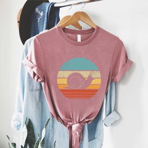 a t - shirt hanging on a rack next to a plant