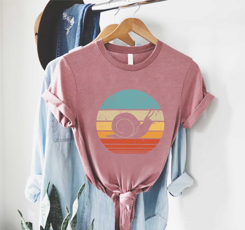 a t - shirt hanging on a rack next to a plant