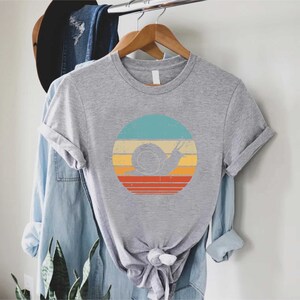 a t - shirt hanging on a clothes rack next to a plant