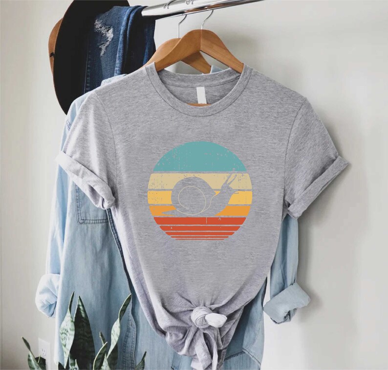 a t - shirt hanging on a clothes rack next to a plant