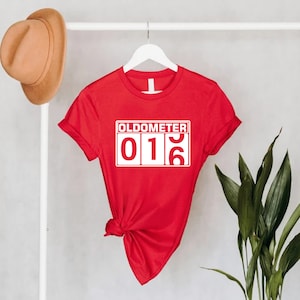 May include: Red t-shirt with a white graphic that says "Oldometer 016".