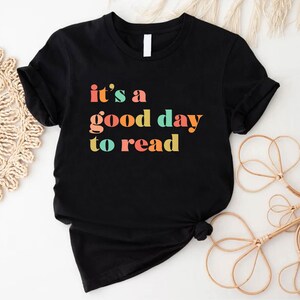 May include: Black t-shirt with the text "it's a good day to read" in colourful letters.