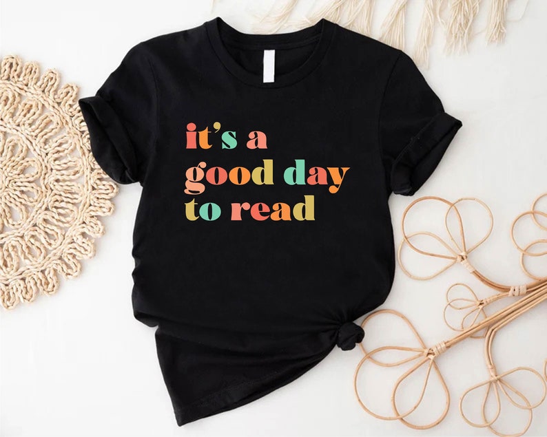 May include: Black t-shirt with the text "it's a good day to read" in colourful letters.