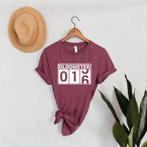 May include: A maroon t-shirt with a white graphic that reads "Odometer 016".