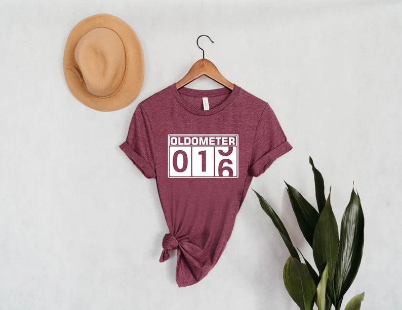 May include: A maroon t-shirt with a white graphic that reads "Odometer 016".