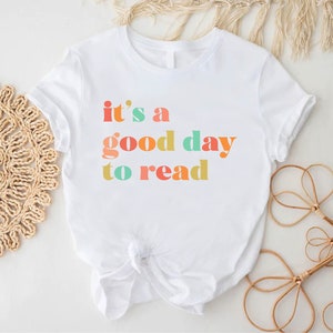 May include: White t-shirt with the text "it's a good day to read" in colourful letters.