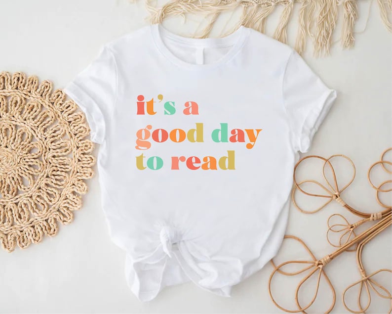 May include: White t-shirt with the text "it's a good day to read" in colourful letters.