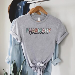 May include: Gray t-shirt with the text "PHARMACY Technician" in colorful letters.