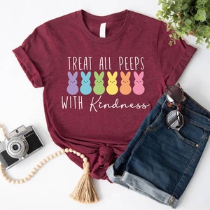 May include: A maroon t-shirt with the text "Treat all peeps with kindness" and a row of colourful marshmallow peeps.