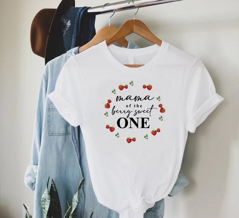 May include: White t-shirt with a graphic of strawberries and the text "mama of the berry sweet one".