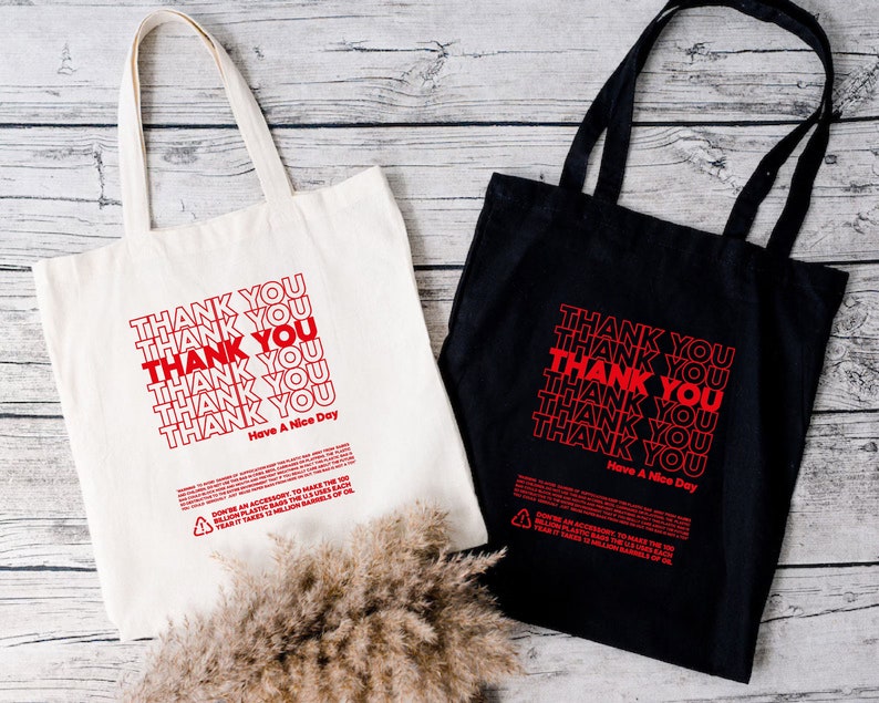 May include: Two tote bags, one white and one black, with the text "THANK YOU" repeated multiple times in red. The text "Have A Nice Day" appears at the bottom of each bag.