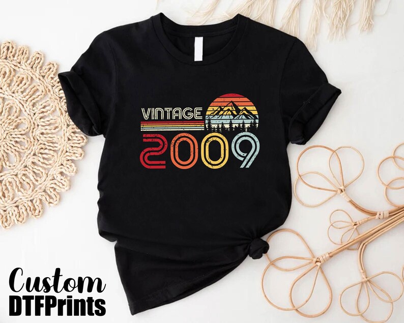 May include: Black t-shirt with a vintage design featuring a mountain range and the text "Vintage 2009".