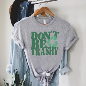 May include: Gray t-shirt with a green graphic that says "Don't Be Trashy" with a green recycle symbol.