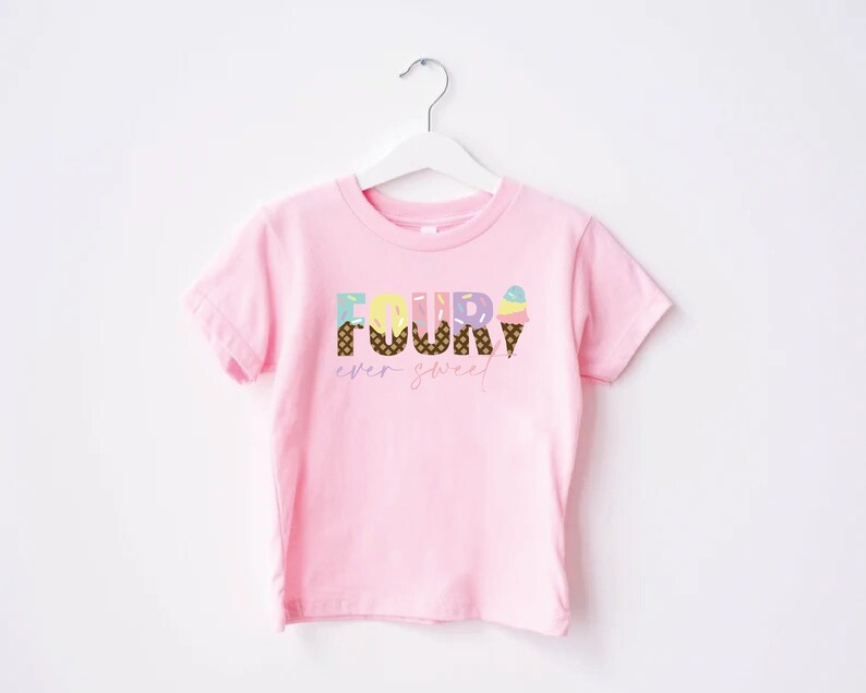 K&ouml;nnte beinhalten: Rosa T-Shirt mit kurzen &Auml;rmeln und dem Text "FOUR" in bunten Buchstaben, die mit Eiswaffeln und Streuseln verziert sind. Der Text "ever sweet" steht unter dem Wort "FOUR".