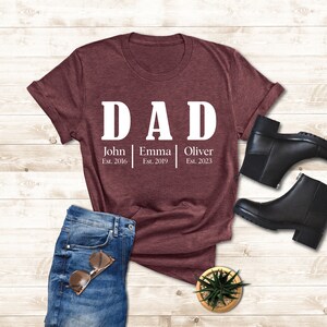 a t - shirt with the words dad on it next to a pair of jeans