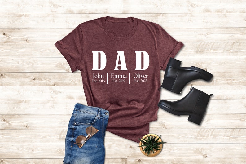 a t - shirt with the words dad on it next to a pair of jeans
