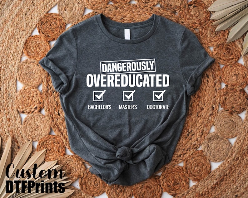 May include: A dark gray t-shirt with the text "Dangerously Overeducated" and checkmarks next to "Bachelor's", "Master's", and "Doctorate".
