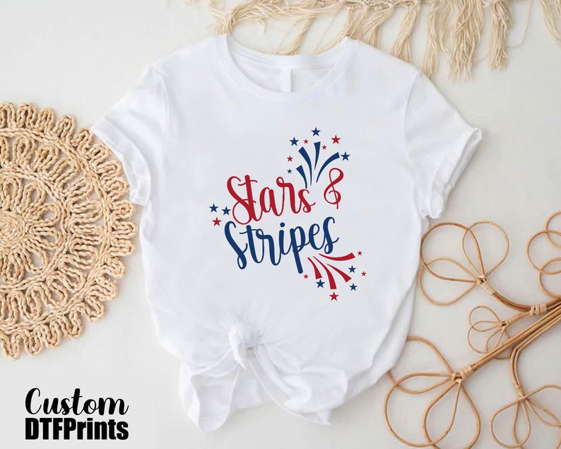 May include: White t-shirt with a red, white, and blue graphic that says "Stars & Stripes".