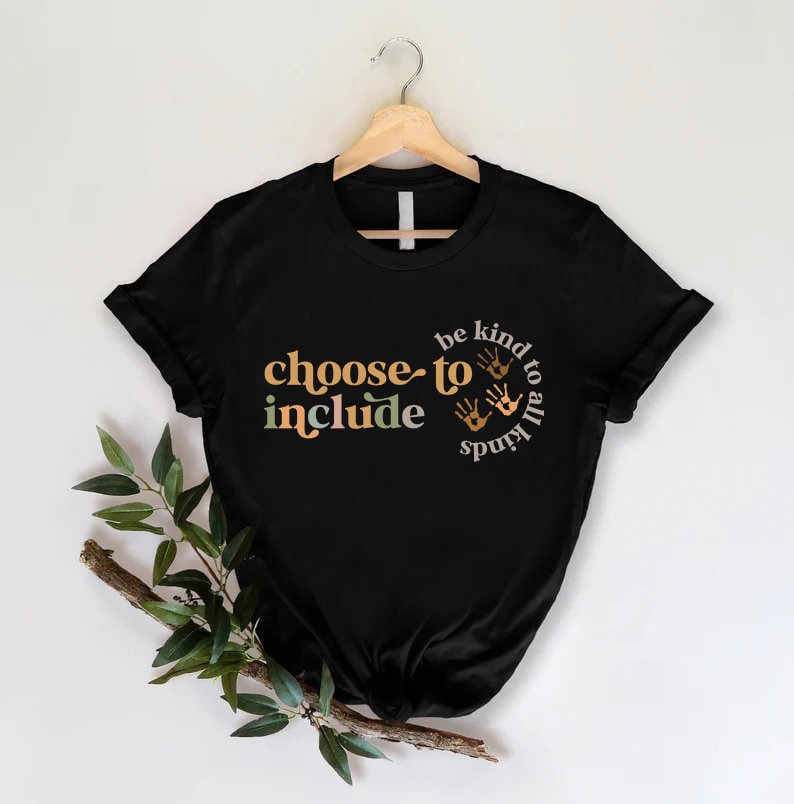 以下が含まれることがあります： オレンジ、緑、ベージュで「choose to include」という言葉が書かれた黒いTシャツ。また、このシャツには「be kind to all kinds」というフレーズと手のひらのプリントが円で描かれています。