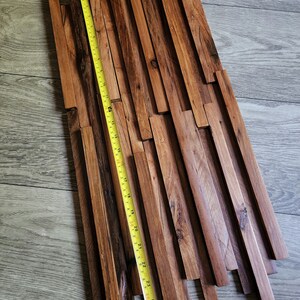 May include: A wooden wall panel made of reclaimed wood planks in various lengths and widths. The panel is approximately 25 inches long and features a natural brown color with a rustic finish.