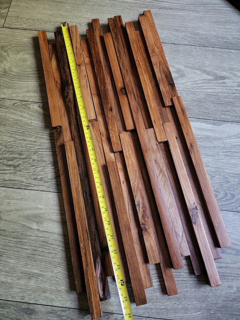 May include: A wooden wall panel made of reclaimed wood planks in various lengths and widths. The panel is approximately 25 inches long and features a natural brown color with a rustic finish.