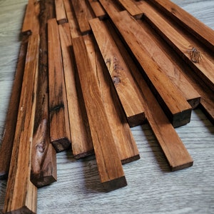 May include: A wall panel made of natural wood planks, arranged in a staggered pattern. The planks are a rich brown color and have a rustic, weathered look. The panel is perfect for adding a touch of natural beauty to any room.