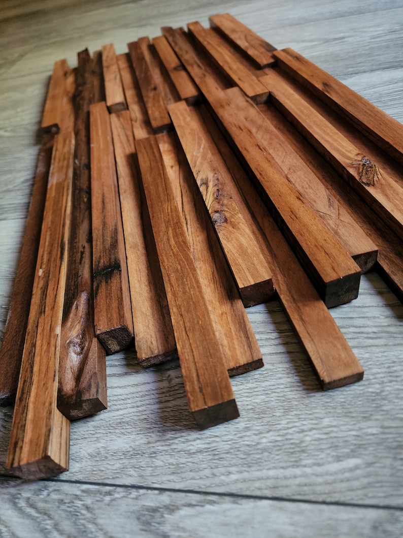 May include: A wall panel made of natural wood planks, arranged in a staggered pattern. The planks are a rich brown color and have a rustic, weathered look. The panel is perfect for adding a touch of natural beauty to any room.