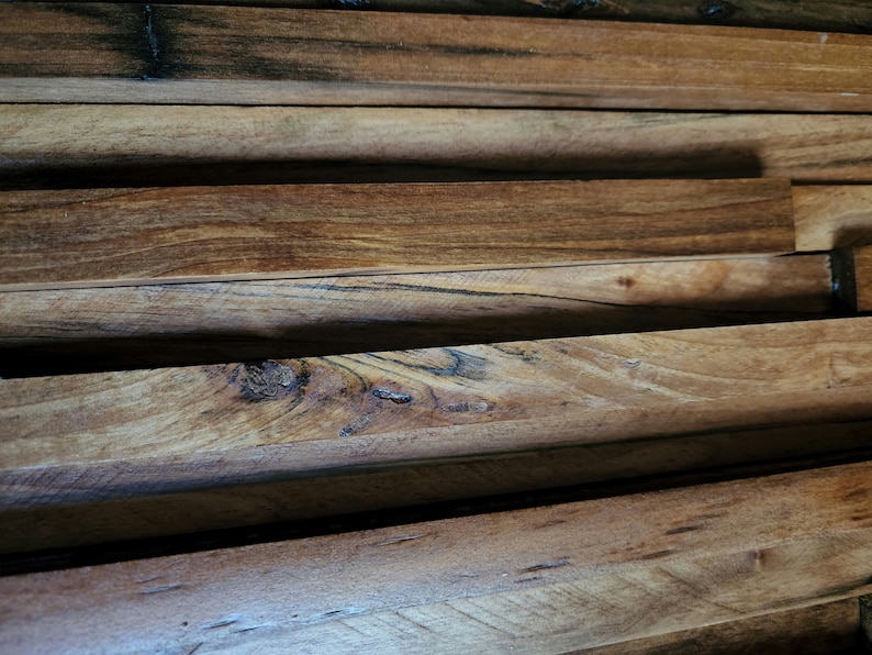 May include: Close-up of a wall made of stacked wooden planks. The planks are arranged in a staggered pattern, creating a textured surface. The wood is a rich brown color with darker streaks and knots.