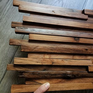 May include: A wall panel made of reclaimed wood with a natural finish. The wood is arranged in a staggered pattern, creating a unique and rustic look.