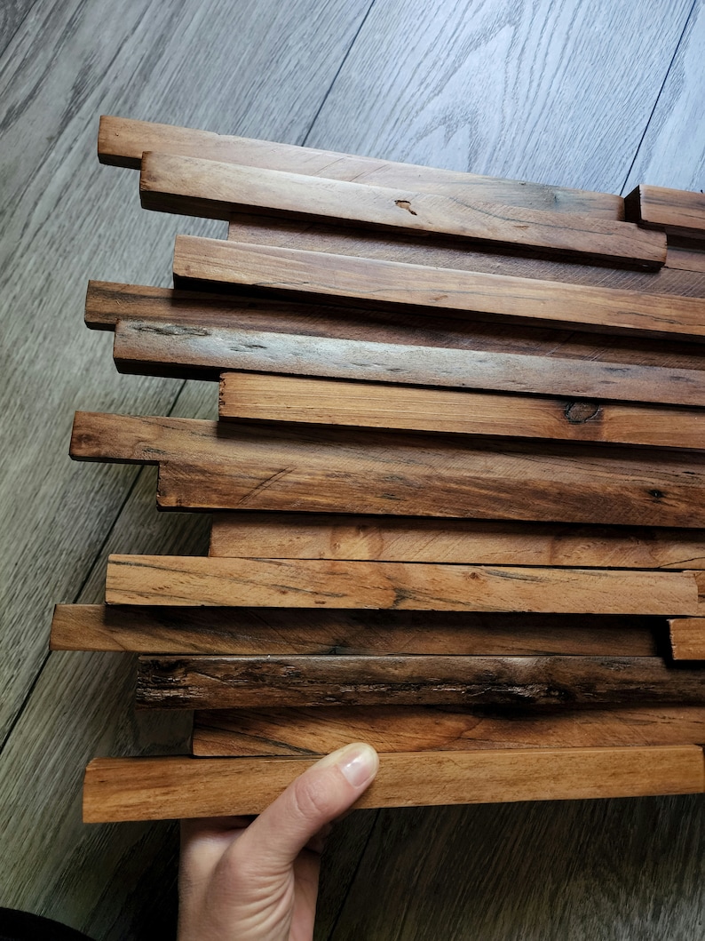 May include: A wall panel made of reclaimed wood with a natural finish. The wood is arranged in a staggered pattern, creating a unique and rustic look.