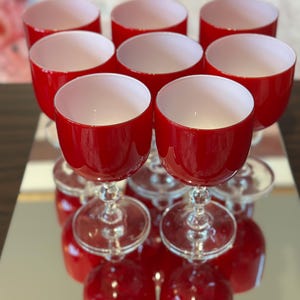 May include: Set of eight red wine glasses with white rims. The glasses have a clear stem and base.