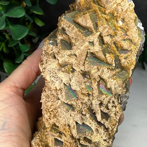 May include: A large, iridescent, brown and gold crystal with a rough, textured surface. The crystal has a layered, stacked appearance with a variety of shapes and sizes.