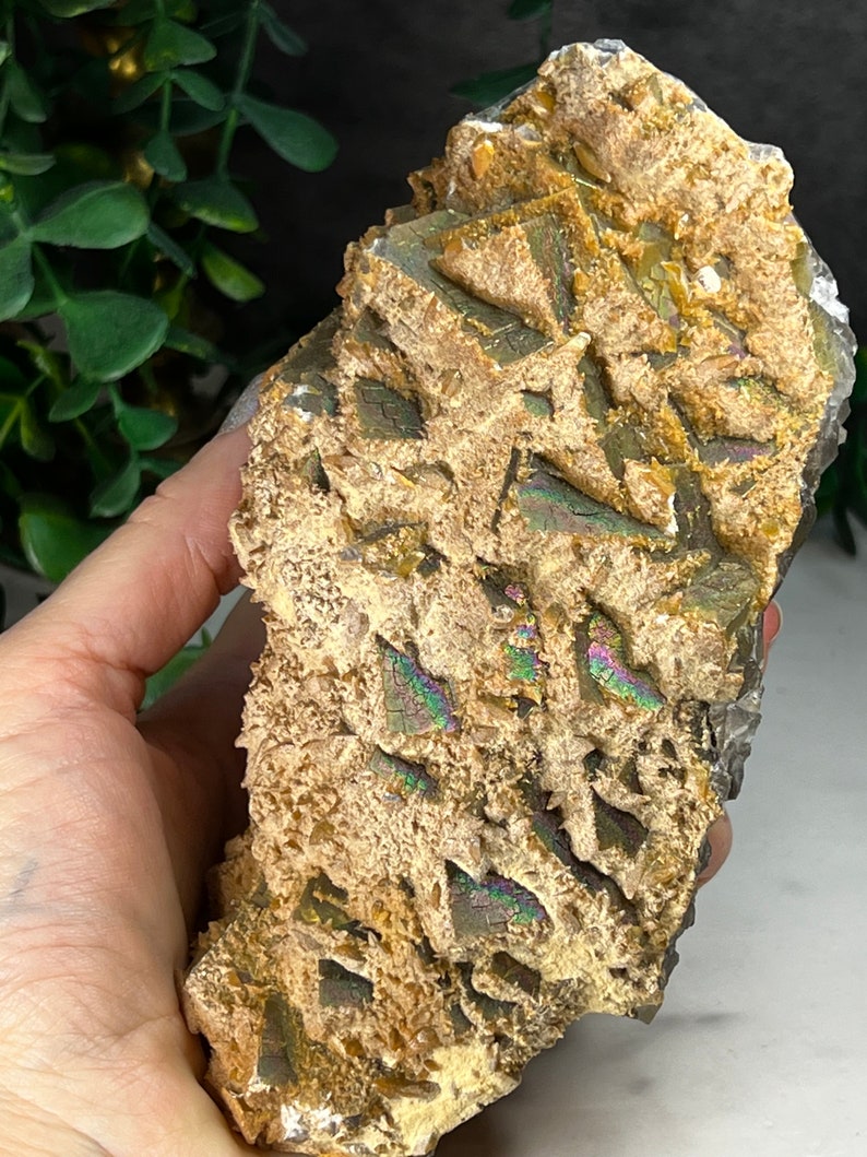 May include: A large, iridescent, brown and gold crystal with a rough, textured surface. The crystal has a layered, stacked appearance with a variety of shapes and sizes.