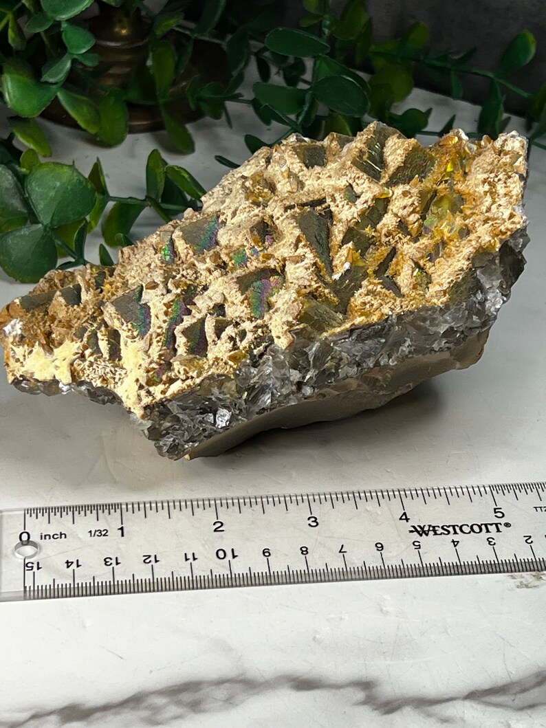 May include: A cluster of iridescent, gold-colored crystals with a rough, textured surface. The crystals are approximately 3 inches in length.
