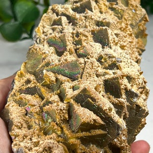 May include: A cluster of iridescent golden crystals with a rough, textured surface. The crystals are arranged in a pyramid shape and have a metallic sheen.