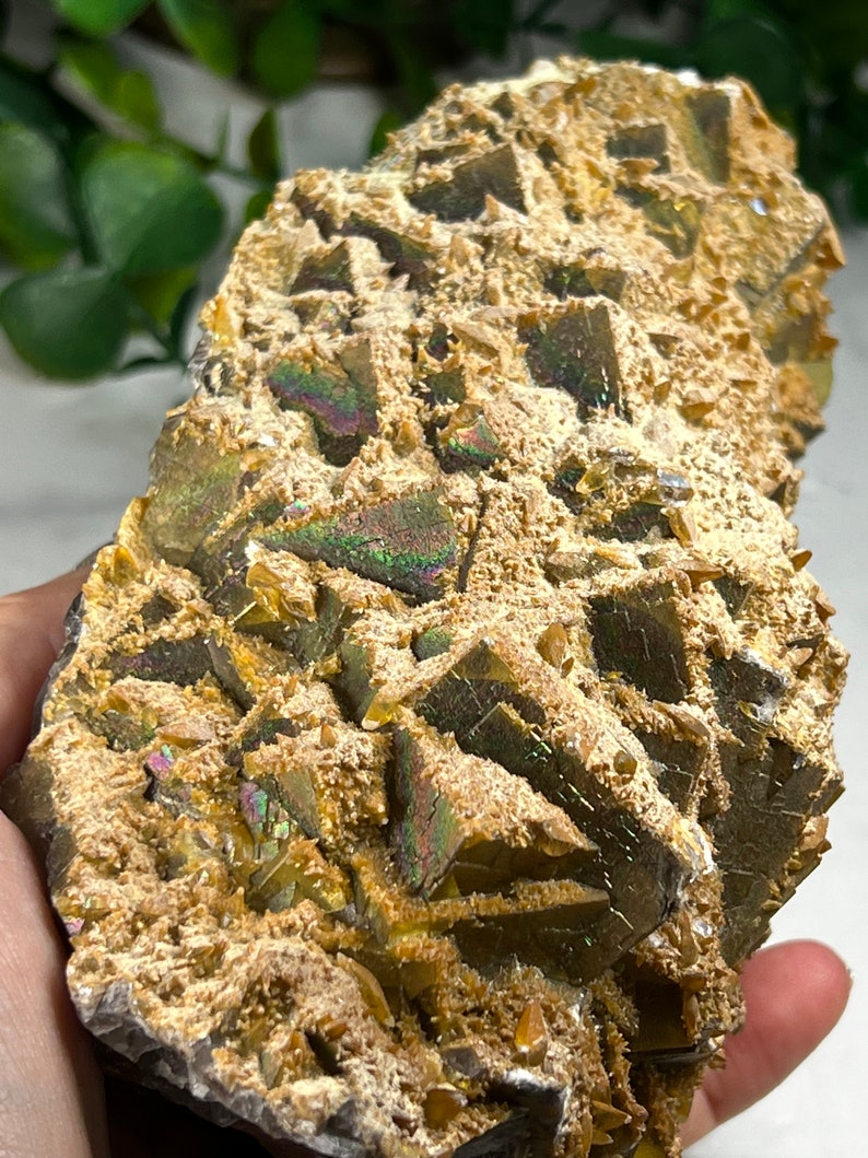 May include: A cluster of iridescent golden crystals with a rough, textured surface. The crystals are arranged in a pyramid shape and have a metallic sheen.