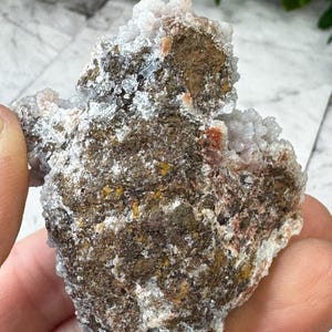 May include: A cluster of white and brown agate with a rough, textured surface. The agate has a natural, earthy look and is a great example of this type of crystal.