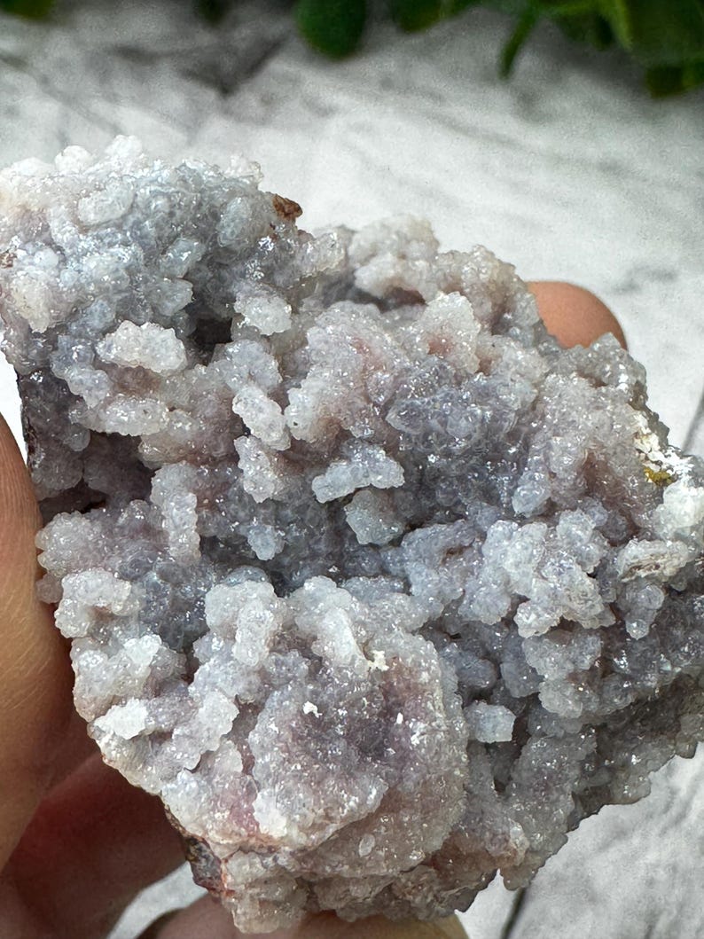 May include: A cluster of small, white and purple crystals with a rough, natural texture. The crystals are densely packed together, creating a unique and interesting pattern.