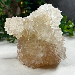 Puede incluir: Un cúmulo de cristales de calcita translúcidos de color marrón claro con una superficie rugosa y texturizada. Los cristales están dispuestos en un patrón aleatorio y orgánico, creando una forma única e interesante.