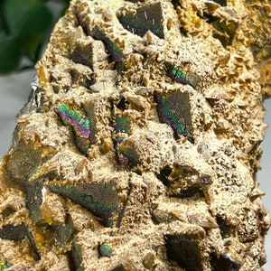 May include: A close-up of a brown and gold iridescent mineral specimen with a rough, textured surface. The mineral has a variety of crystal shapes and sizes, and it is covered in a layer of fine, sparkling crystals.