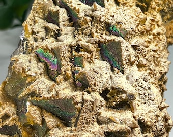 May include: A close-up of a brown and gold iridescent mineral specimen with a rough, textured surface. The mineral has a variety of crystal shapes and sizes, and it is covered in a layer of fine, sparkling crystals.